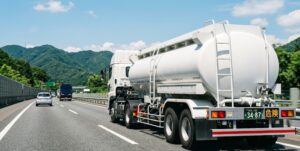 幹線道路を走行するタンク型セミトレーラ。特殊車両通行許可申請における車種区分と総重量緩和のイメージ。